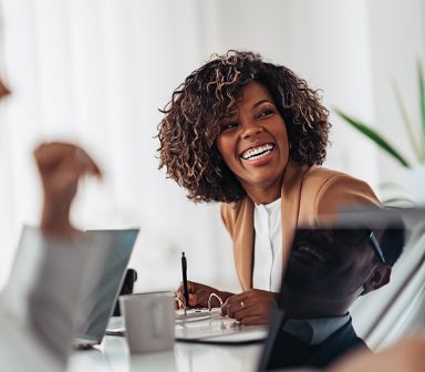 Portrait of cheerful african american businesswoman discussing and smiling at the meeting with colleagues
